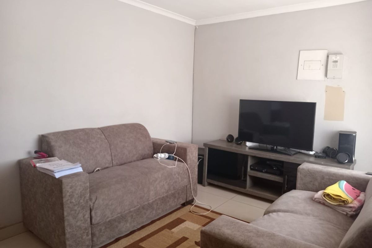A living room featuring tiled flooring, recessed downlighting, and coved cornicing, providing a functional space for relaxation.