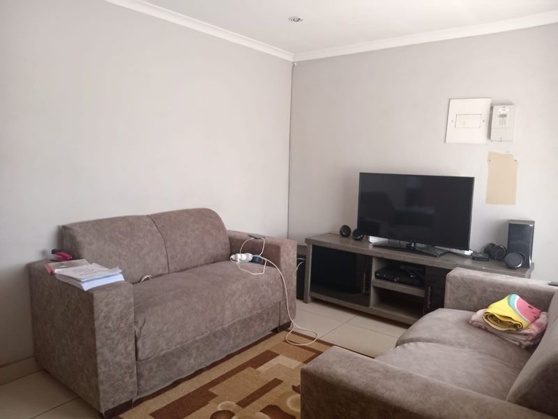 A living room featuring tiled flooring, recessed downlighting, and coved cornicing, providing a functional space for relaxation.