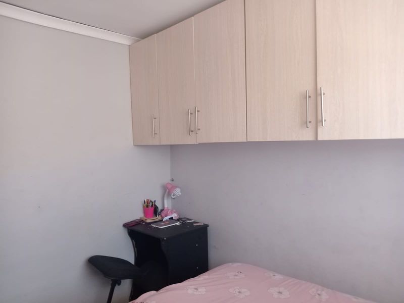 A bedroom featuring light wood-tone built-in overhead cabinetry providing ample storage space.