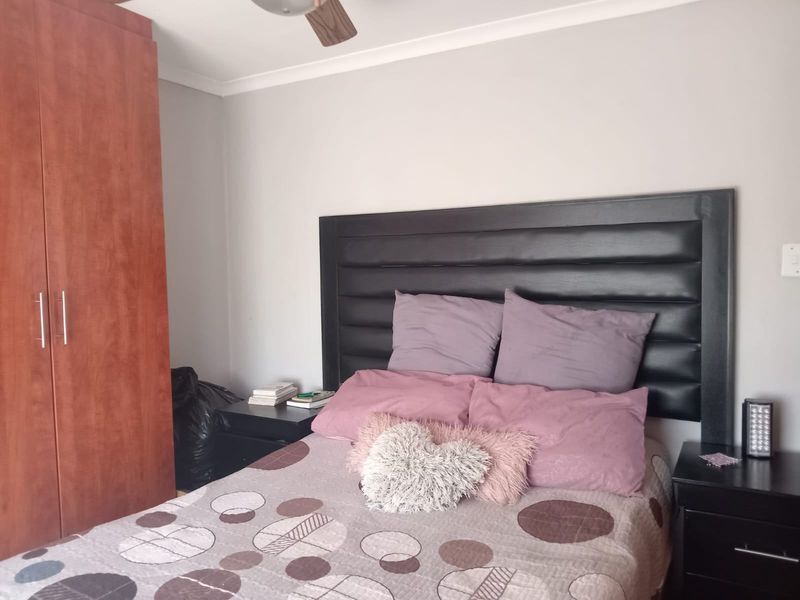 A functional bedroom featuring a built-in wooden wardrobe and a ceiling fan, providing essential storage and climate control.