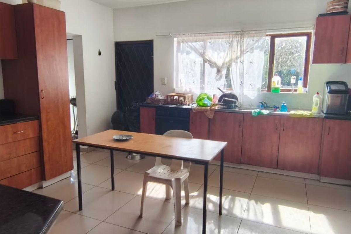 A functional kitchen featuring wood-finish cabinetry, dark countertops, and tiled flooring, offering a practical layout with ample storage space.
