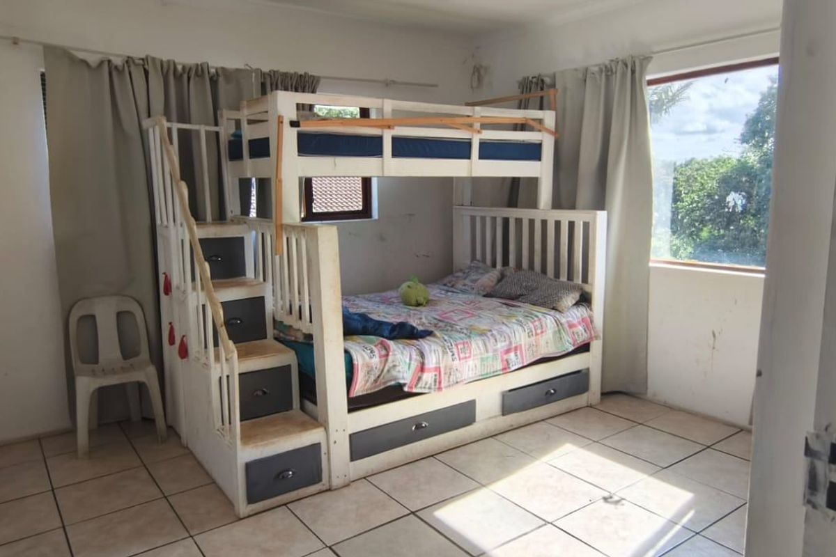 A bedroom featuring tiled flooring and built-in cupboards, requiring minor cosmetic updates to the wall finishes.