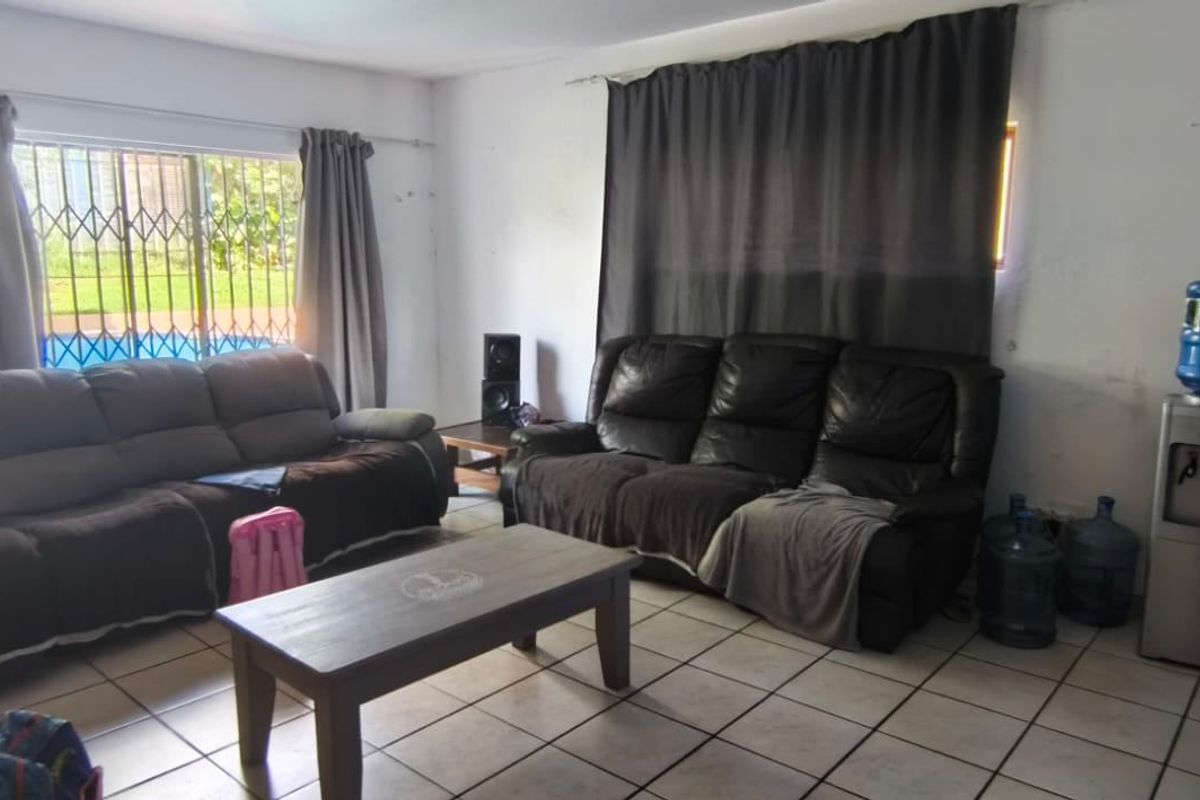 A living room featuring tiled flooring and windows fitted with security bars, offering a functional space with potential for cosmetic updates.