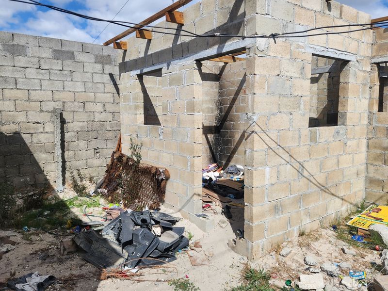 An unfinished residential structure in shell condition, featuring exposed concrete block walls and timber roof framing, requiring significant completion and development.