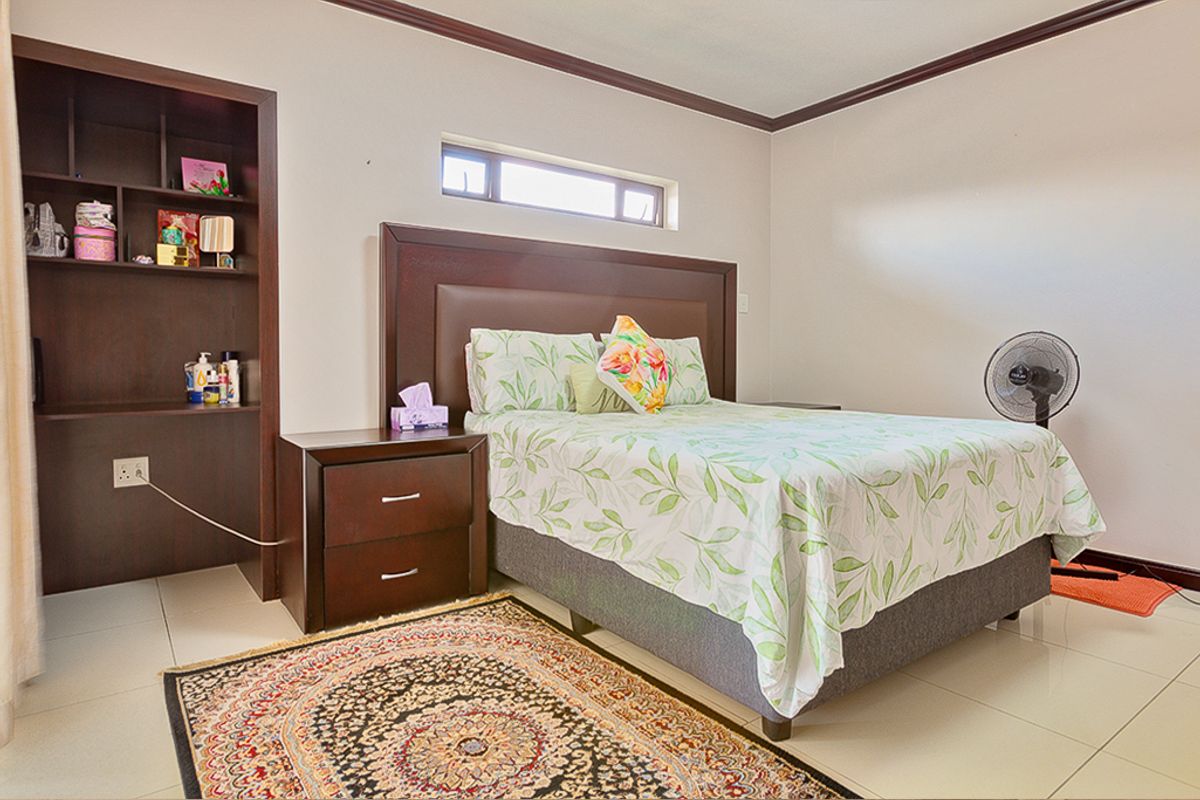 A well-maintained bedroom featuring tiled flooring, a horizontal clerestory window, and integrated built-in shelving.