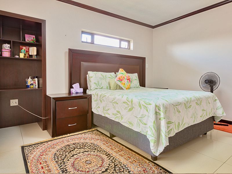 A well-maintained bedroom featuring tiled flooring, a horizontal clerestory window, and integrated built-in shelving.