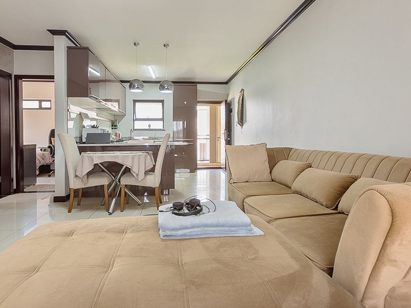 Open-plan living and kitchen area featuring modern glossy cabinetry, stone countertops, and polished tiled flooring, creating a cohesive and functional living space.