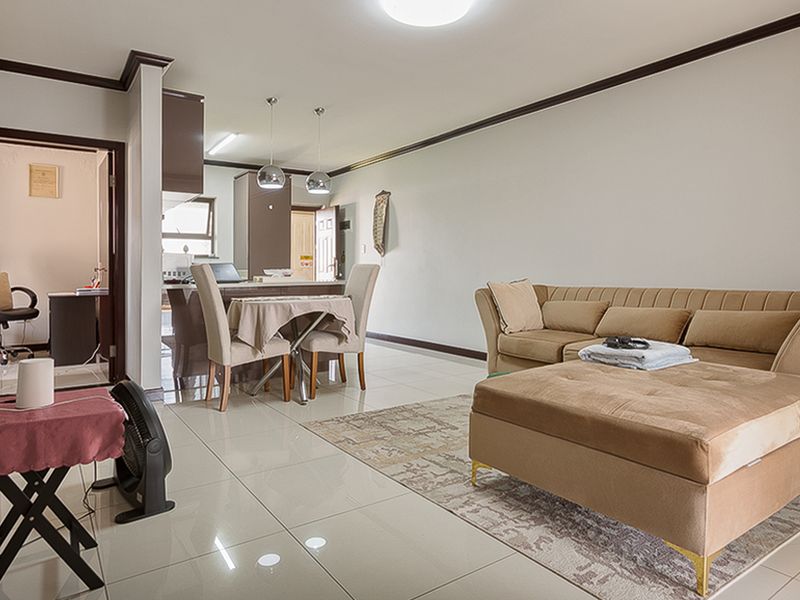 Spacious open-plan living and dining area featuring polished porcelain floor tiles, modern pendant lighting, and seamless flow into the kitchen space.
