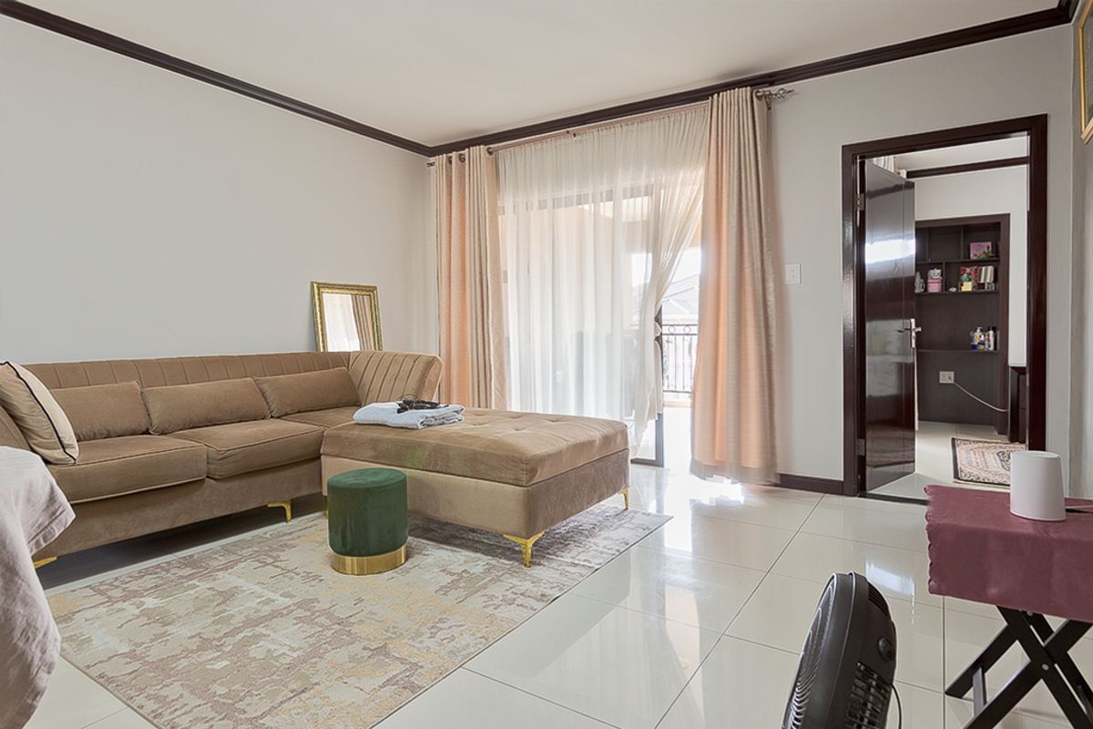 A bright living room featuring polished tile flooring, crown molding, and a sliding glass door providing access to an outdoor balcony area.