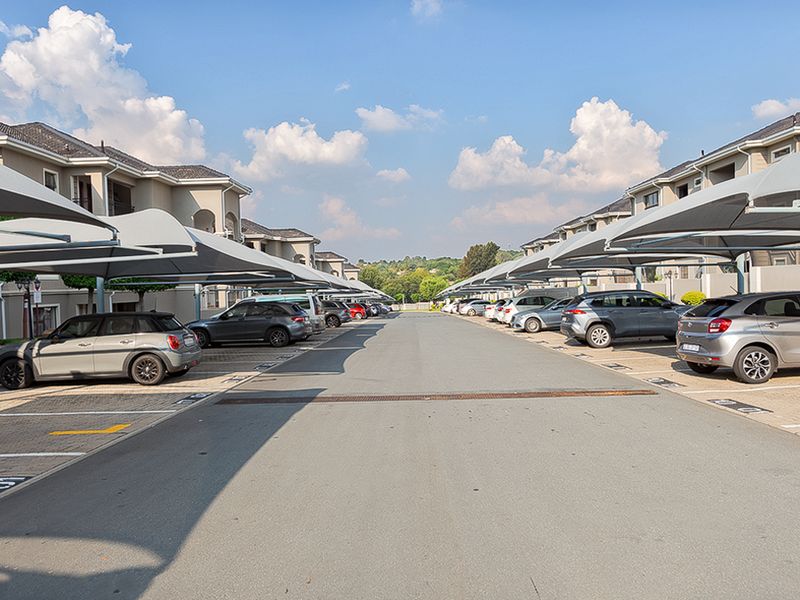 A well-maintained outdoor parking area featuring designated bays with shade cloth carports for residential apartment units.