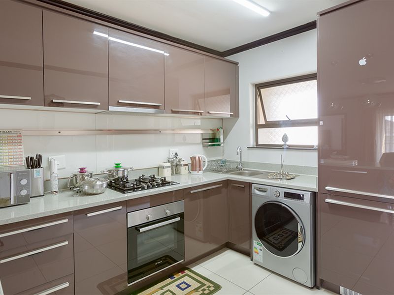 Modern kitchen featuring high-gloss cabinetry, stone countertops, built-in oven, gas hob, and integrated appliance space with tiled flooring.