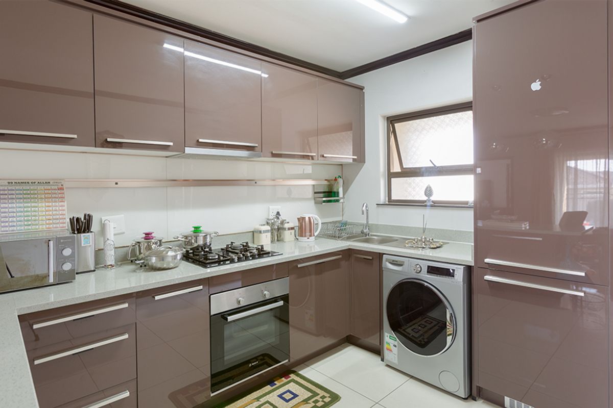 Modern kitchen featuring high-gloss cabinetry, stone countertops, built-in oven, gas hob, and integrated appliance space with tiled flooring.