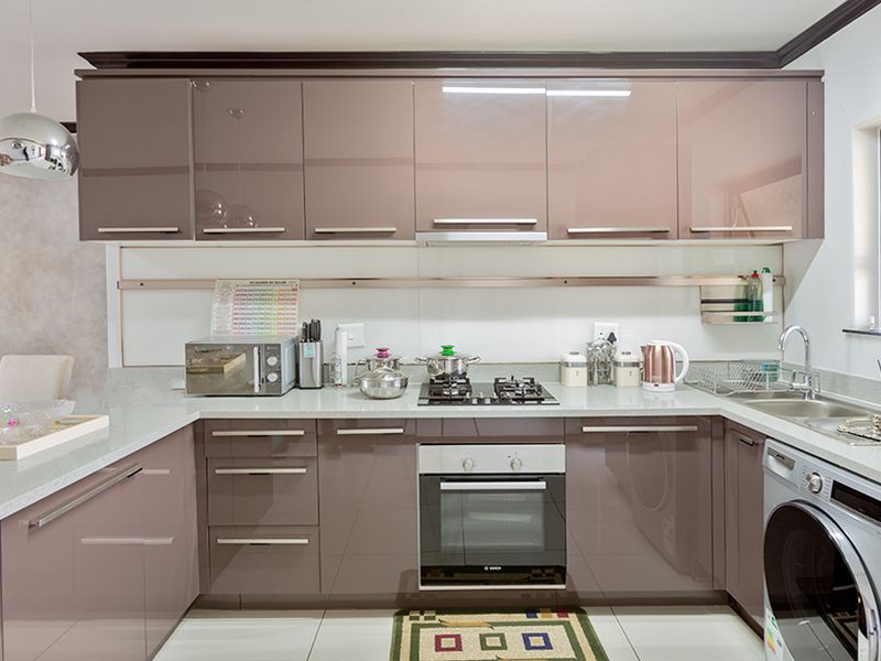 Modern kitchen featuring high-gloss cabinetry, stone countertops, integrated oven, gas hob, and stainless steel sink with tiled flooring.