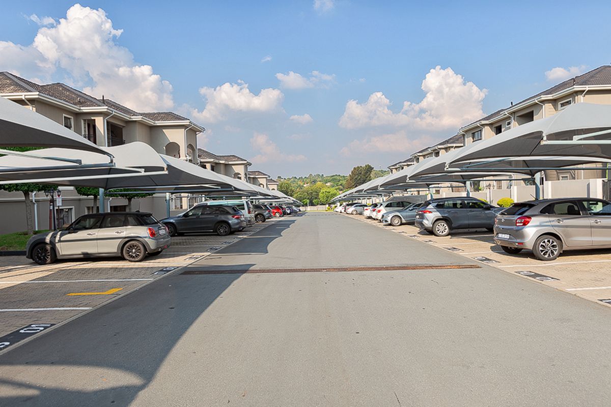 A well-maintained outdoor parking area featuring designated bays with shade cloth carports for residential apartment units.