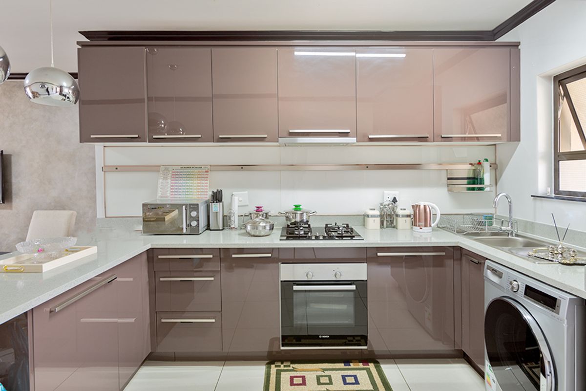 Modern kitchen featuring high-gloss cabinetry, stone countertops, integrated oven, gas hob, and stainless steel sink with tiled flooring.