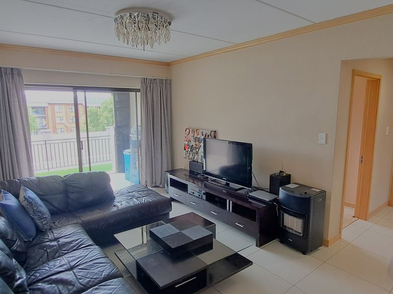 A living room featuring tiled flooring, a ceiling light fixture, and a sliding glass door providing access to a balcony.