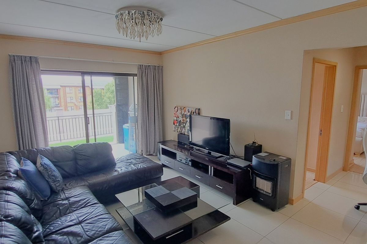 A living room featuring tiled flooring, a ceiling light fixture, and a sliding glass door providing access to a balcony.