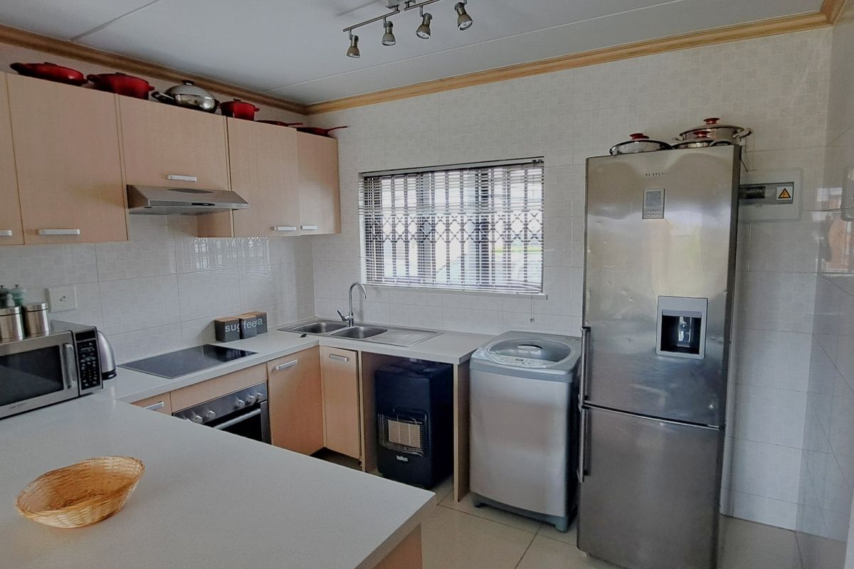 Functional kitchen featuring light wood-tone cabinetry, laminate countertops, tiled splashbacks, and integrated appliances, offering a practical layout for daily meal preparation.