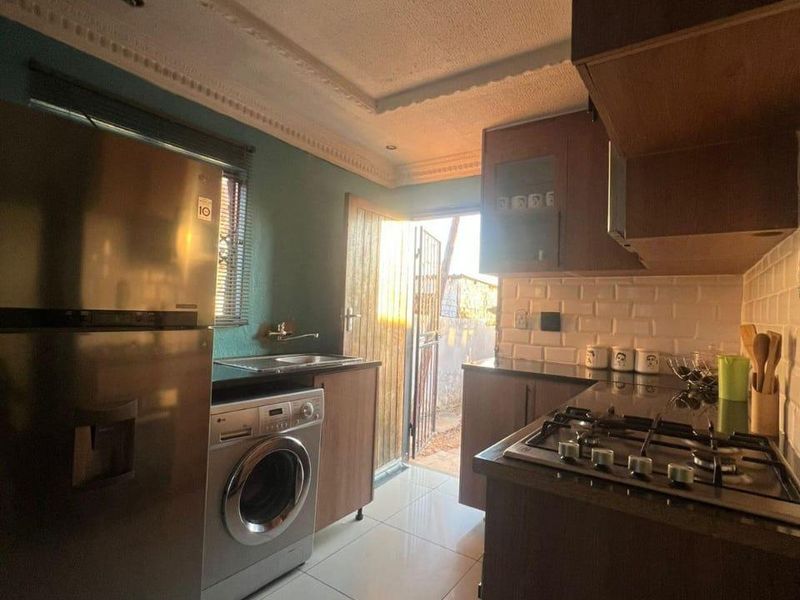 Compact kitchen featuring dark wood cabinetry, gas hob, subway tile backsplash, and direct access to the exterior.
