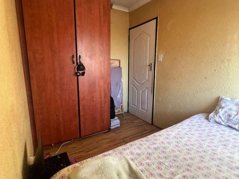 A compact bedroom featuring laminate flooring, a built-in wardrobe, and coved ceiling details, offering a functional space ready for cosmetic updates.