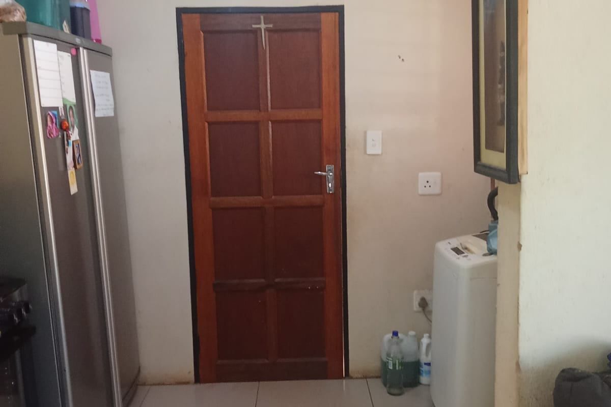 A functional kitchen area featuring tiled flooring, a solid wooden door, and standard electrical fixtures.