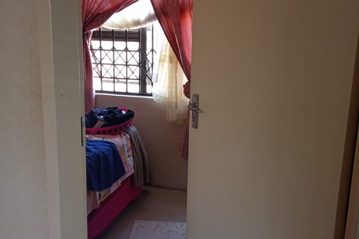 A view into a bedroom featuring tiled flooring and a window fitted with a security gate.