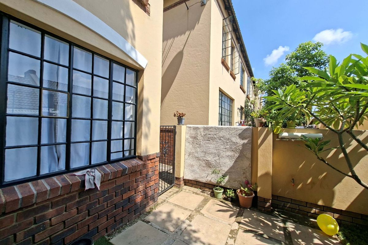 A private rear courtyard featuring paved flooring, brick-accented exterior walls, and steel-framed windows, providing a functional outdoor space for the townhouse.