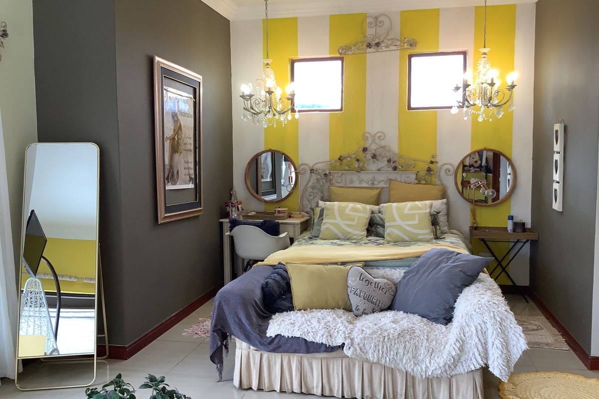 A well-maintained bedroom featuring tiled flooring, decorative ceiling roses, and dual crystal chandeliers, providing a bright and characterful living space.