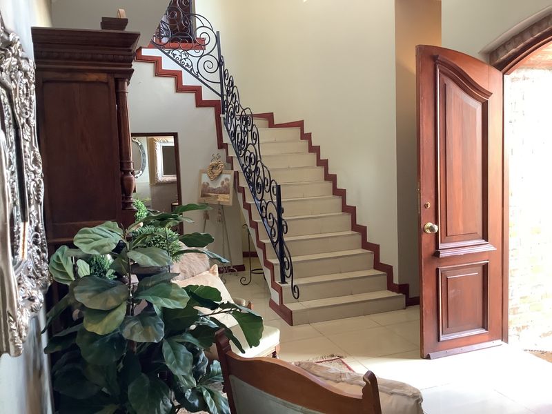 Welcoming entrance hall featuring a tiled staircase with decorative wrought iron balustrades and a solid wood front door.