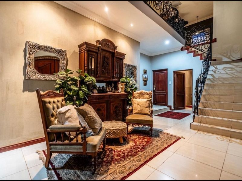 Spacious entrance hall featuring elegant tiled flooring, a grand staircase with ornate wrought iron balustrades, and classic solid wood interior doors.