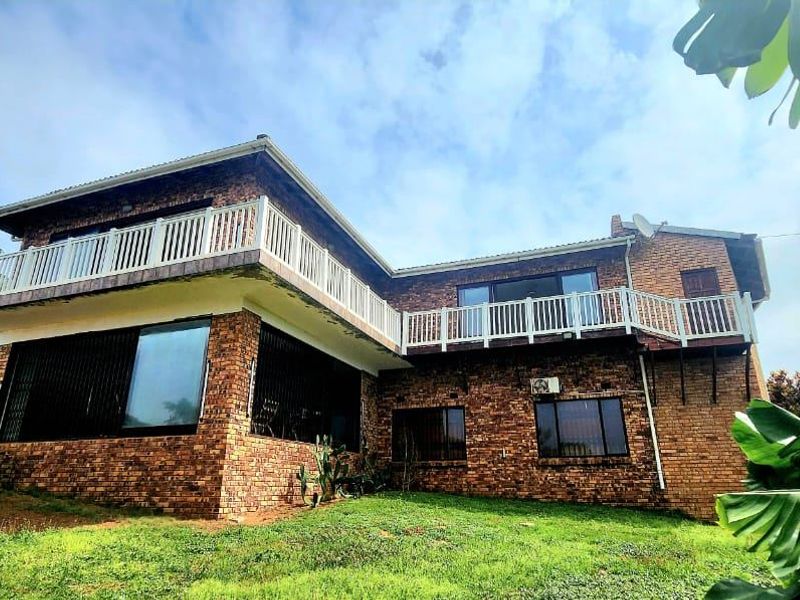 Rear view of a two-story exposed brick house featuring an upper-level balcony with white balustrades and security-fitted windows.