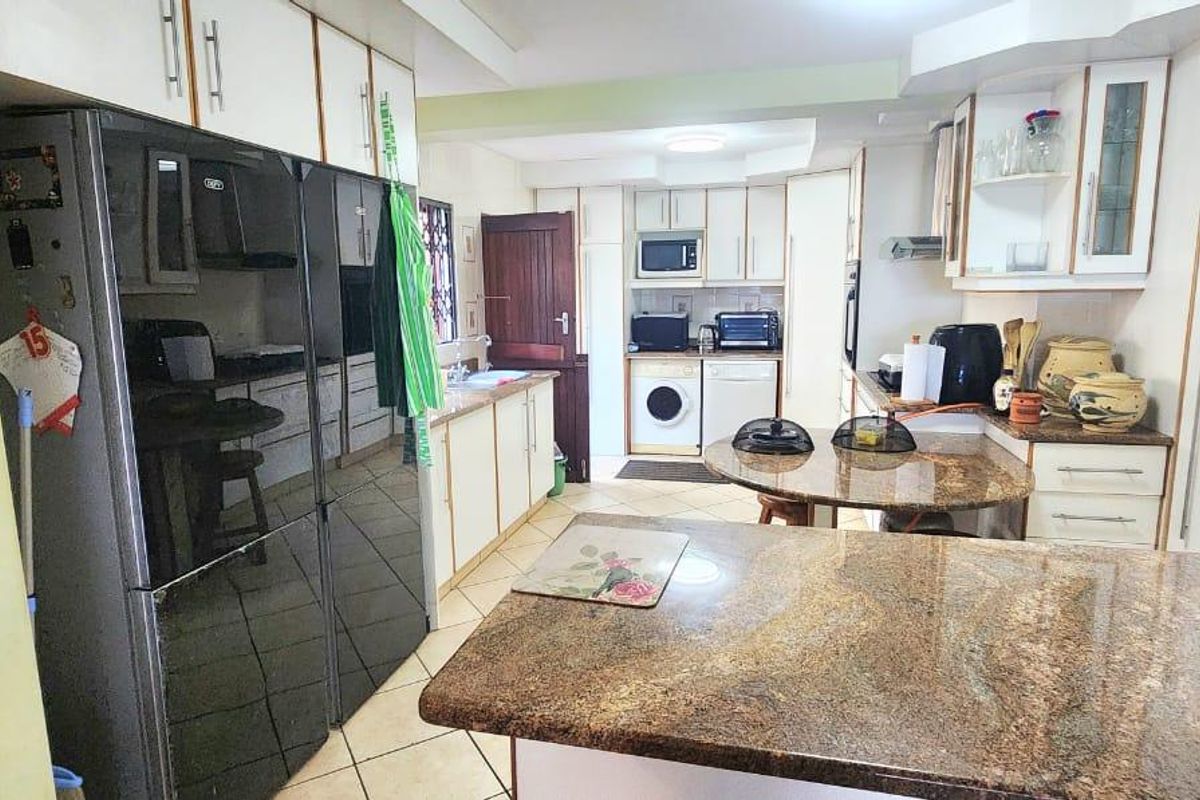 A functional kitchen featuring granite countertops, ample built-in cabinetry, and tiled flooring, offering a practical layout for daily meal preparation.