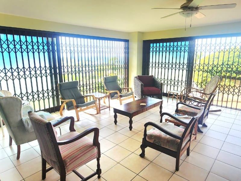 A spacious covered patio featuring tiled flooring, a ceiling fan, and extensive sliding security gates providing access to the outdoor area.
