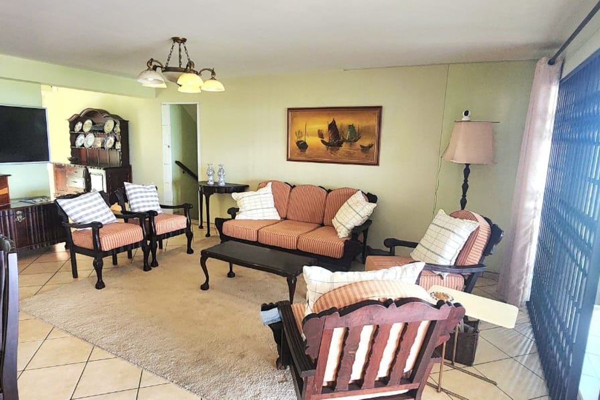 Spacious living room featuring ceramic tile flooring and large sliding glass doors with security gates, providing access to the outdoor area.