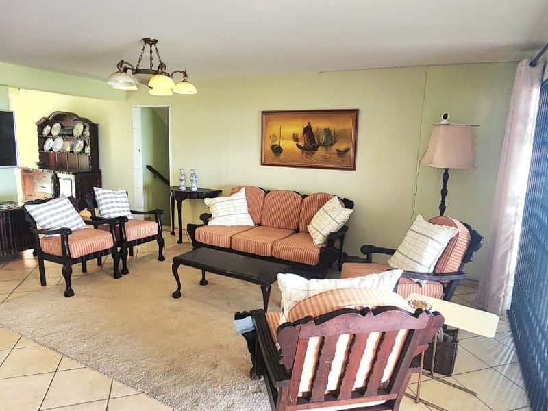 Spacious living room featuring ceramic tile flooring and large sliding glass doors with security gates, providing access to the outdoor area.