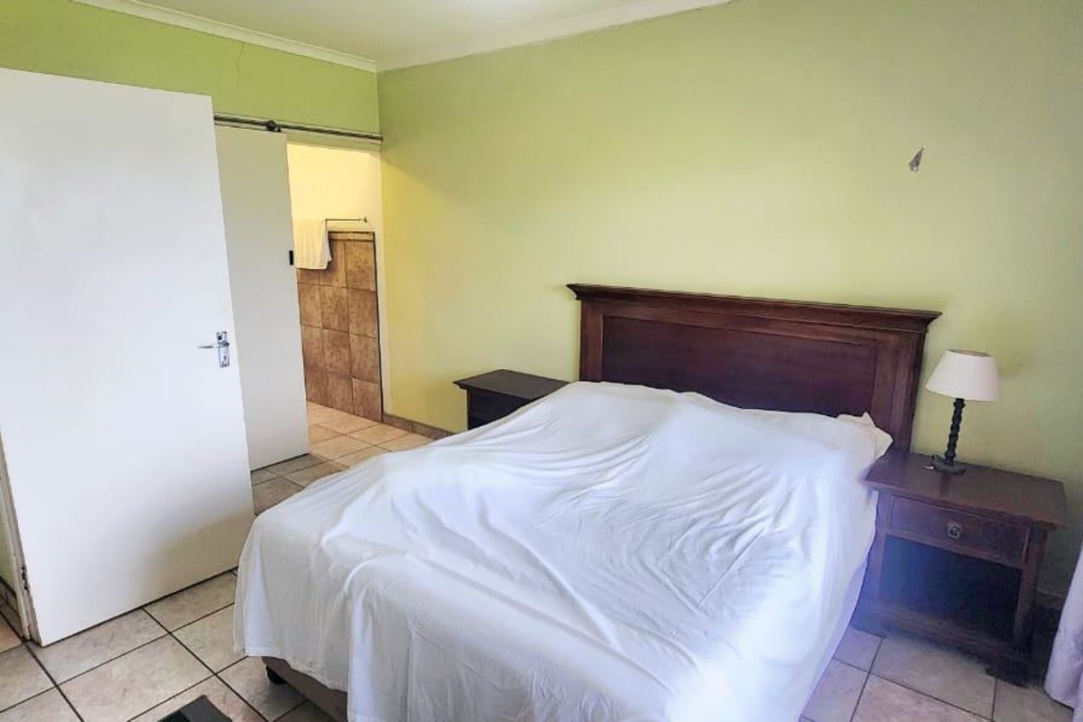 A bedroom featuring tiled flooring and direct access to an en-suite bathroom, requiring cosmetic updates to the wall finishes.