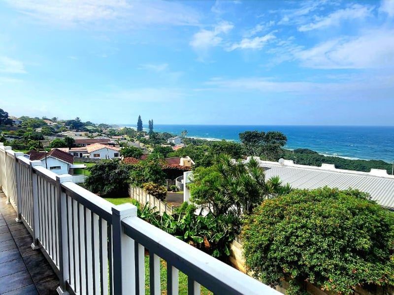 A spacious balcony featuring tiled flooring and a secure railing, offering expansive panoramic views of the coastline and surrounding residential neighborhood.