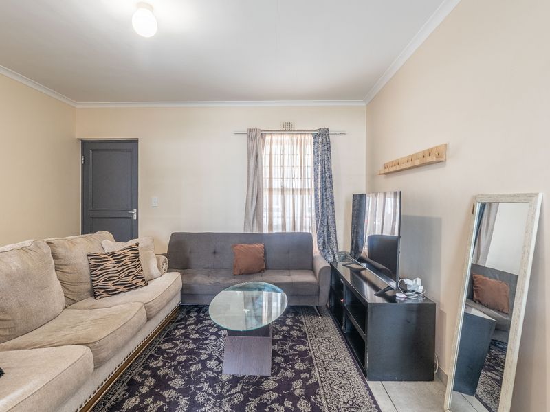 A functional living room featuring neutral wall finishes, cove cornicing, and a standard internal door, providing a comfortable and well-lit living space.