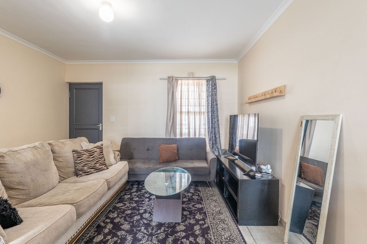 A functional living room featuring neutral wall finishes, cove cornicing, and a standard internal door, providing a comfortable and well-lit living space.