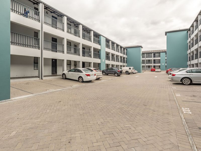 Exterior view of a multi-story apartment complex featuring paved parking bays and building facades with balcony balustrades.