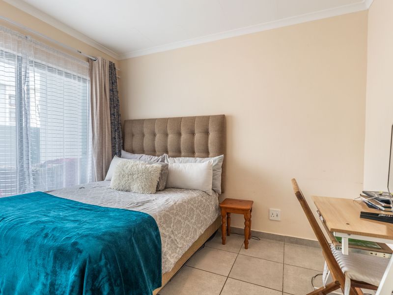 A functional bedroom featuring tiled flooring and a sliding glass door providing natural light.