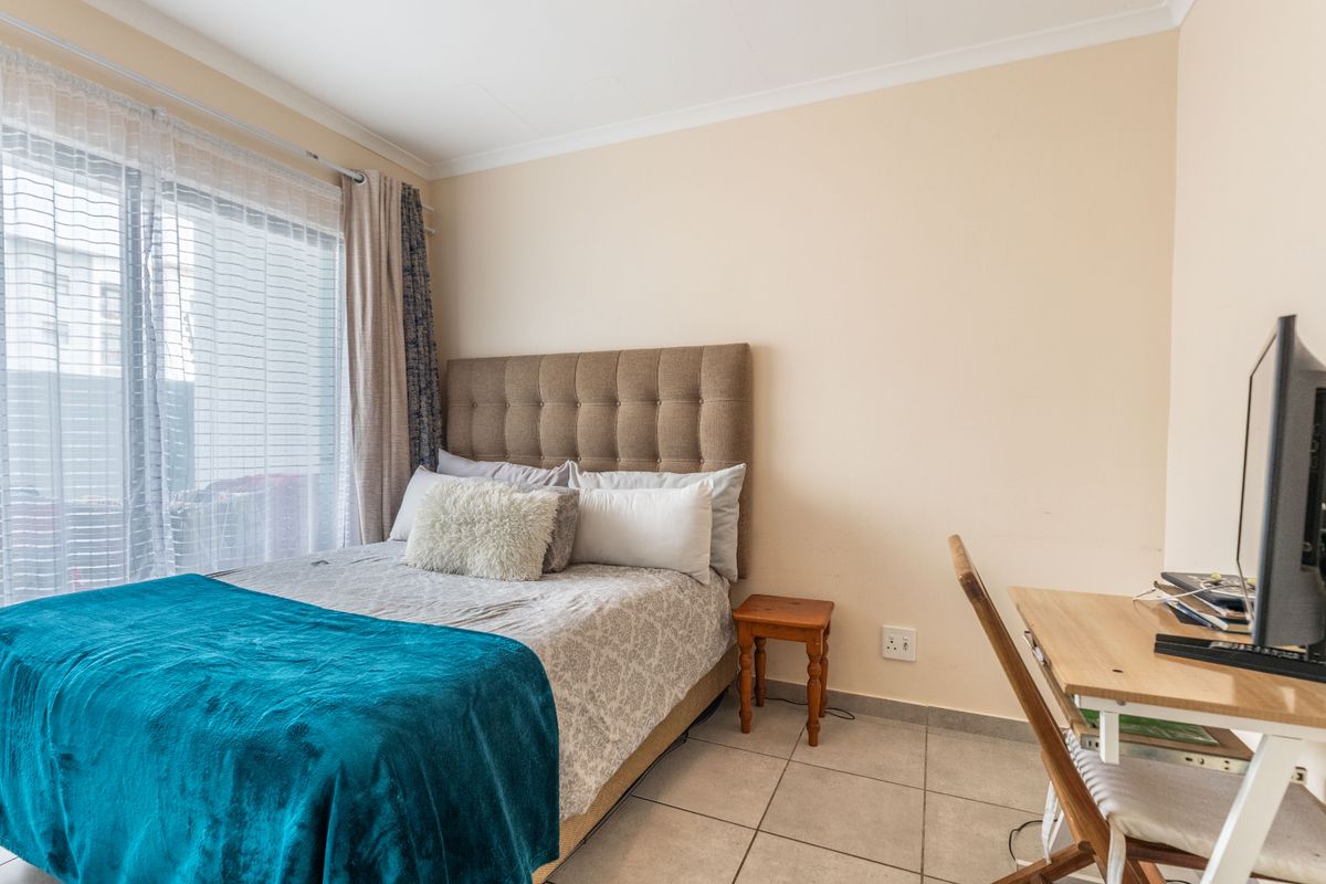 A functional bedroom featuring tiled flooring and a sliding glass door providing natural light.