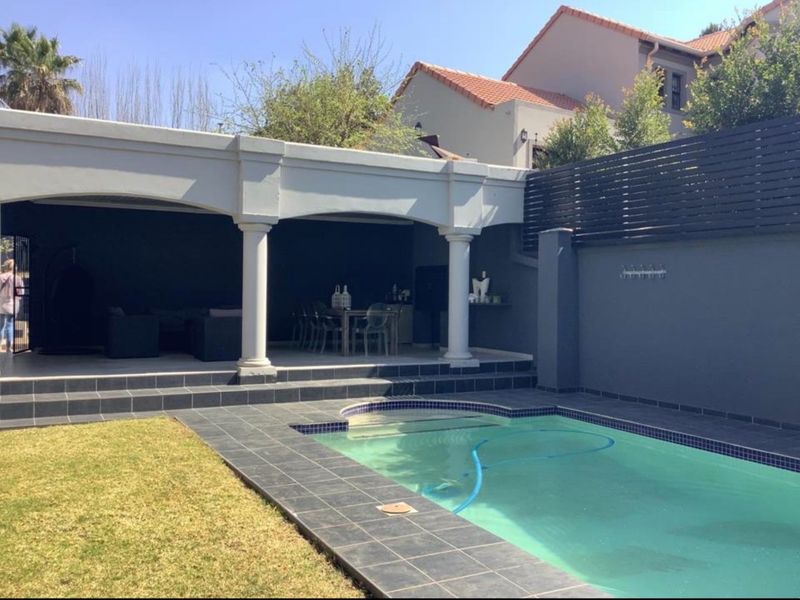 Outdoor pool area featuring a tiled surround, a covered patio with architectural columns, and a private garden space with boundary walling.