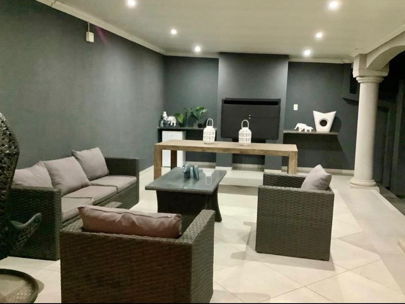 Covered patio area featuring a built-in braai, recessed downlighting, and tiled flooring, providing a functional space for outdoor entertaining.