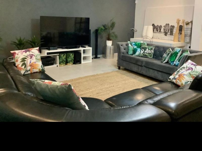 A spacious living room featuring a dark accent wall, tiled flooring, and recessed ceiling lighting, providing a comfortable area for relaxation.