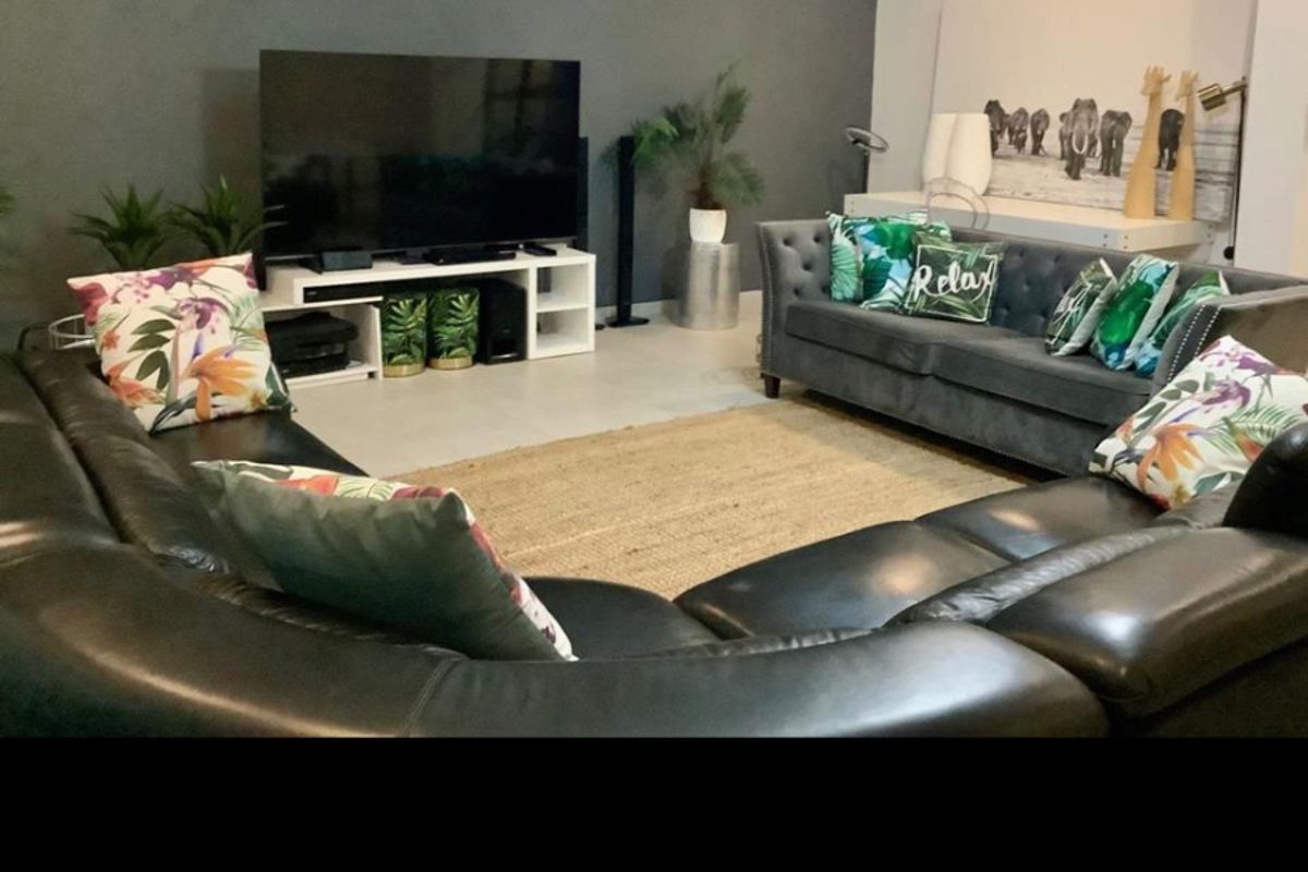 A spacious living room featuring a dark accent wall, tiled flooring, and recessed ceiling lighting, providing a comfortable area for relaxation.