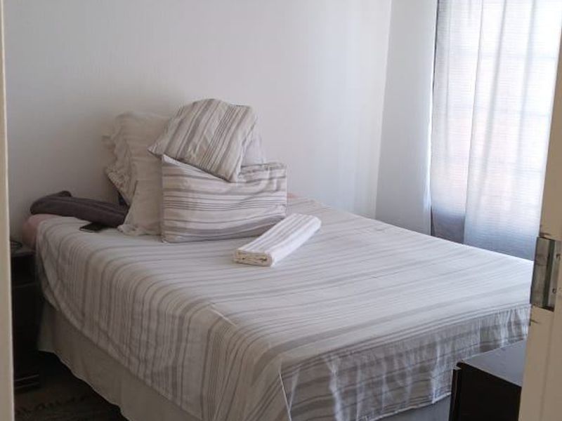 A standard bedroom featuring neutral wall finishes, carpeted flooring, and a window with fitted curtain rails.