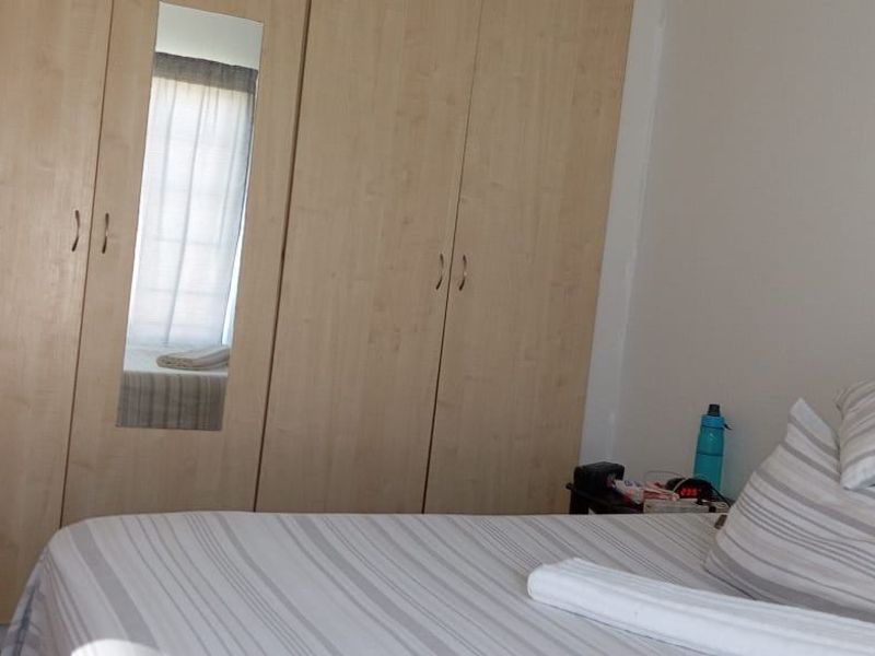 A bedroom featuring light wood-finish built-in wardrobes with an integrated mirror.