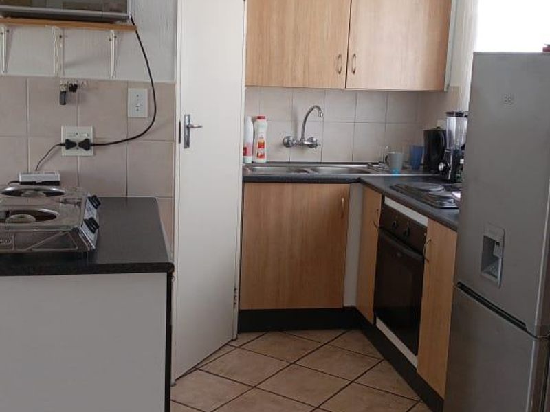 A functional kitchen featuring laminate cabinetry, built-in oven, hob, and tiled flooring, offering a practical layout with potential for modern updates.