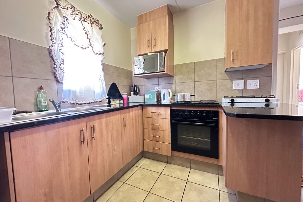 Functional kitchen featuring laminate cabinetry, granite countertops, built-in oven, gas hob, and tiled finishes, offering a practical layout for daily cooking.